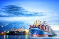 Logistics and transportation of international container cargo ship with ports crane bridge in harbor at dusk for logistics import Royalty Free Stock Photo