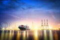 Logistics and transportation of International Container Cargo ship with ports crane bridge in harbor at Twilight sky for logistic Royalty Free Stock Photo