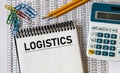 LOGISTICS - word in a notebook on the background of a table with numbers, calculator and pencils