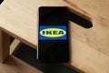 Logo of Ikea on iPhone 11 screen on a wooden bench.