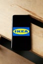 Logo of Ikea on iPhone 11 screen on a wooden bench.