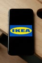 Logo of Ikea on iPhone 11 screen on a wooden bench.