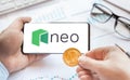 Logo of Neo Smart Economyl in tablet. Cryptocurrency coin token. Trading blockchain platform to buy,sell on decentralized exchange