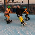 Logoisk. Belarus. 01.07.2023. Four teenage snowboarders ski down the slope of a snow-covered mountain in special gear