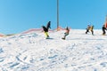 Logoisk. Belarus. 01.03.2023. A group of children snowboarders with a coach descend from a snow-covered mountain