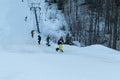 Logoisk. Belarus. 01.13.2023. A group of happy teenage snowboarders in special equipment go up the mountain using a drag lift.