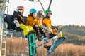 Logoisk. Belarus. 01.12.2023. Happy teenage snowboarders in special equipment ride a chair lift uphill.