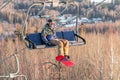 Logoisk. Belarus. 01.13.2023. A male snowboarder in special gear rides a chairlift uphill. Winter extreme sport.