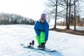 Logoisk. Belarus. 01.14.2023. A snowboarder girl is preparing to descend from a snow-covered mountain in special equipment. Winter