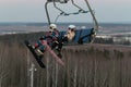 Logoisk. Belarus. 01.12.2023. Teenage snowboarders in special equipment ride a chair lift uphill.