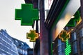 Logos of French Pharmacy Association in shape of green cross hanging from building