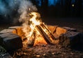 Logs arranged in a teepee shape burn brightly within a stone fire Royalty Free Stock Photo