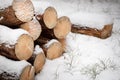 Logs piled on the street. Stack of cut wood under the snow. It`s winter and it`s snowing Royalty Free Stock Photo