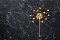 Lollipop and round colored candy pills on a black stone background. Top view, flat lay, copy space