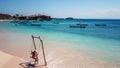 Lombok - A girl swinging on a wooden swing by the seashore