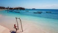 Lombok - A girl swinging on a wooden swing by the seashore