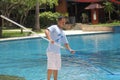 lombok, Indonesia, january 30, 2022, a hotel employee wearing a blue t-shirt is cleaning the swimming pool with a net stick