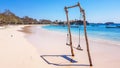Lombok - A swing made of wood on a pink beach