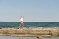 Ãâlonde woman walking on sea rocks Royalty Free Stock Photo