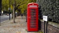 London, Britain-September, 2019: Red telephone booth on street with trees and people. Action. Red public telephone booth