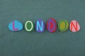 London, creative composition with multi colored stone letters over green sand