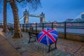 London, England - British style umbrella on a bench with iconic illuminated Tower Bridge at background