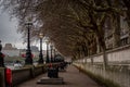 LONDON, ENGLAND, DECEMBER 29, 2018: Perspective view of the riverside of Thames in London, with street lamps and trees decorated Royalty Free Stock Photo