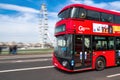 English double-decker bus crossing westminster bridge with the ferris wheel `the london eye` in the distance