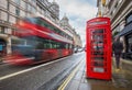 London, England - Iconic blurred red double-decker bus on the move with traditional red telephone box Royalty Free Stock Photo