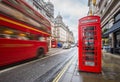 London, England - Iconic blurred vintage red double-decker bus on the move with traditional red telephone box Royalty Free Stock Photo