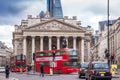 London, England - Iconic red double decker busses on the move and black and green london taxies with the Royal Exchange building