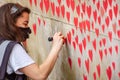 LONDON, ENGLAND- 31 March 2021: Volunteer adding love hearts to The National Covid Memorial Wall near St Thomas` Hospital