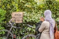 LONDON, ENGLAND- 15 May 2021: Muslim woman taking a photograph of a placard on a fence at a March For Palestine demonstration