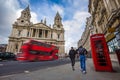 London, England - Tourist couple walking by a traditional red telephone box with red double-decker bus Royalty Free Stock Photo