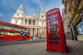 London, England - Traditional red telephone box with iconic red double-decker bus on the move at St.Paul`s Cathedral Royalty Free Stock Photo