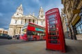 London, England - Traditional red telephone box with iconic red double-decker bus on the move at St.Paul`s Cathedral