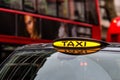 London, England, UK - December 31, 2019:  A british london black taxi cab sign with defocused  red bus in background Royalty Free Stock Photo