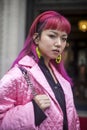 Stylish attendees gathering outside 180 The Strand for London Fashion Week. A girl with pink hair in purple culottes and a pink qu