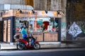 Delivery driver and motor scooter outside Middle Eastern food kiosk