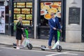 Well dressed man and woman on rental electric scooters