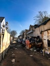 A London mews with abandoned cars and a skip that with rubbish.