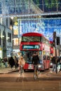 Cyclists ahead of a Red London Double Decker Bus with Oxford Street illuminated Christmas decorations in the background