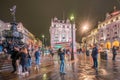 London - October 2019: tourists by the statue of Anteros at Piccadilly Circus at night after rain