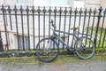 London - old bicycle leaning against wrought iron fence outside building with bay window well in background - selective focus