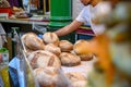 A shopkeeper selecting loaves for a customer at a bread stall in Borough Market, London