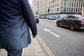 London street scene with man in suit walking past cars in road