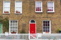 London typical house with brick wall, red door and white fence