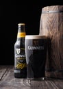 LONDON, UK - APRIL 27, 2018: Bottle and original glass of Guinness draught stout beer  next to old wooden barrel Royalty Free Stock Photo