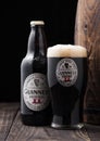LONDON, UK - APRIL 27, 2018: Bottle and original glass of Guinness extra stout beer  next to old wooden barrel Royalty Free Stock Photo