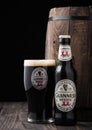 LONDON, UK - APRIL 27, 2018: Bottle and original glass of Guinness extra stout beer  next to old wooden barrel Royalty Free Stock Photo